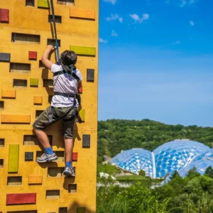 A Kid climbing on the hangloose climb activity, eden project in the background